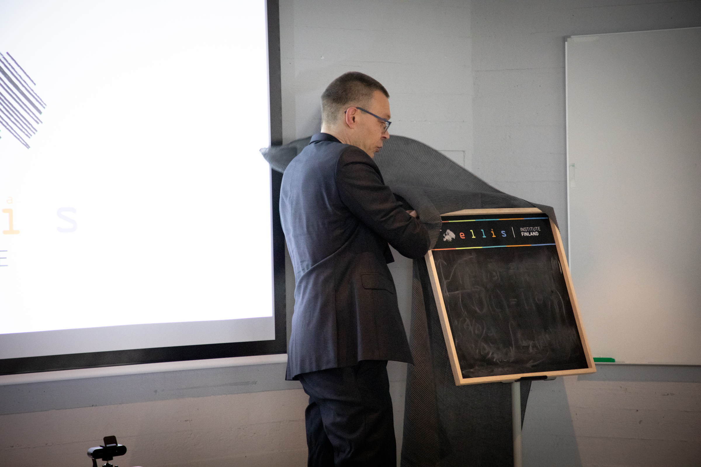 Man lifts cover off of a square blackboard on a stand
