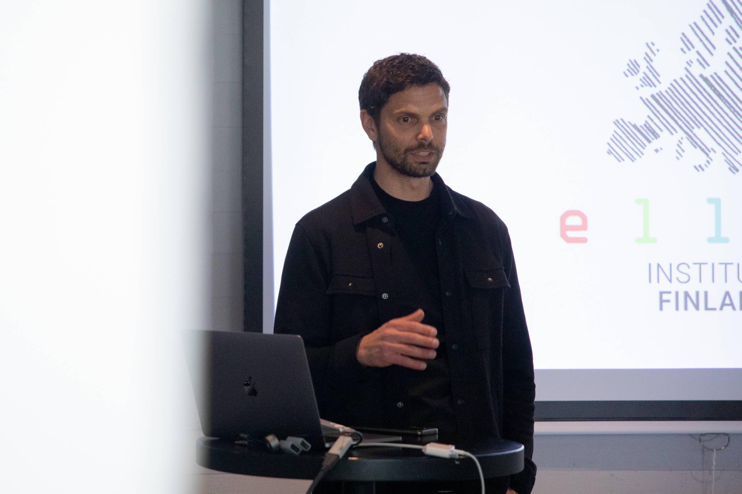 Man speaking in front of a screen