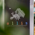 Roll-up with ELLIS logo in the front and two persons standing on the background.