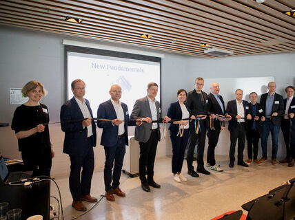 People standing in a line holding a ribbon