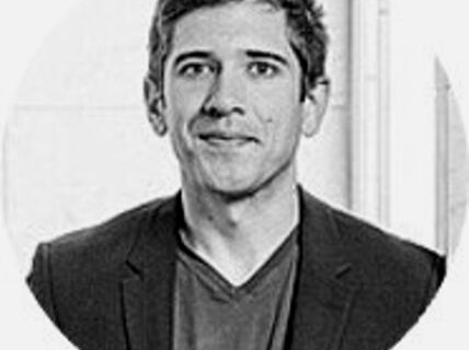 Portrait of a dark-haired man with a black jacket.