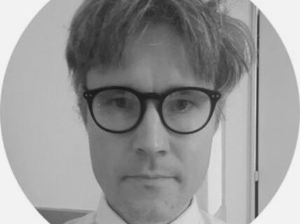 Portrait of a blond-haired man with glasses.