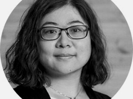 Portrait of a dark-haired woman with glasses.