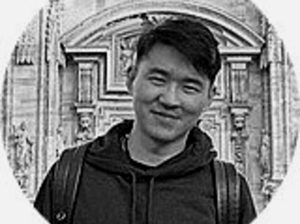 Portrait of a smiling dark-haired man in a hoodie.