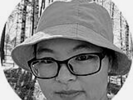 Portrait of a woman with glasses and a hat.