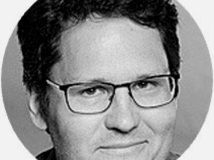 Portrait of a dark-haired man with glasses.