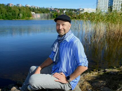 Man seated on a rock by a body of water