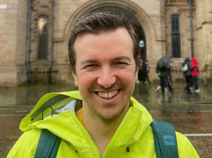 Photo of smiling person in front of University of Manchester building