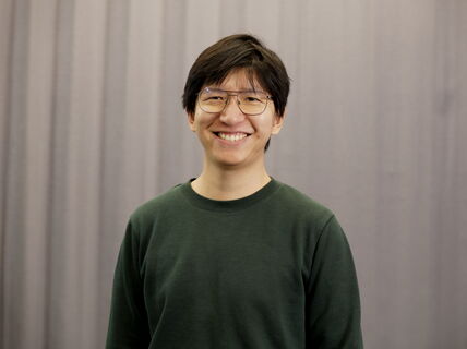 Smiling person wearing glasses against a grey background