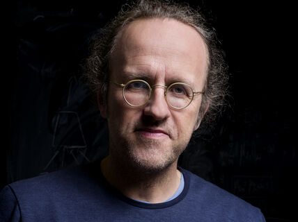 Person wearing round spectacles against a black background