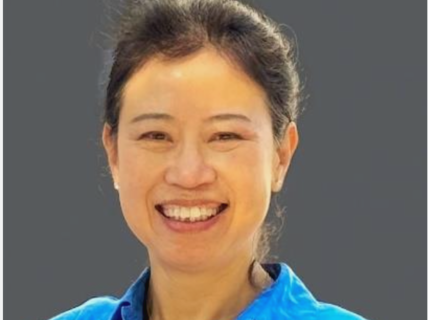 Smiling person wearing a blue shirt against a grey background