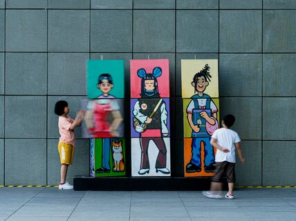 Two children playing with a colorful character combination installation (blocks that can be flipped)