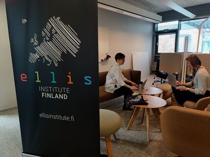 Black ELLIS Institute Finland banner with two people sitting off to the side with laptops