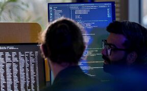 Two men in front of computer screens.