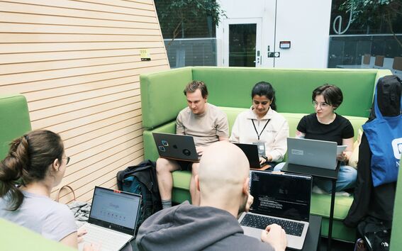People sitting on green couches and working on laptops