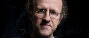 Person wearing round spectacles against a black background