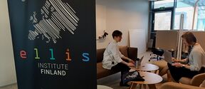 Black ELLIS Institute Finland banner with two people sitting off to the side with laptops