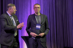 One person clapping and another holding a clear glass award