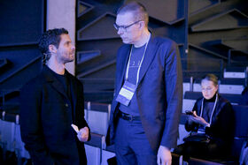 Two people in dark clothing having a conversation