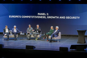 Six people sit on a stage with text in background: PANEL I: EUROPE'S COMPETITIVENESS, GROWTH AND SECURITY