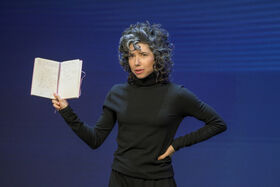 Meredith Whitaker speaking with an opened book in hand