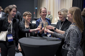 Five people smile while clinking glasses