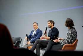 Three people with microphones seated in chairs