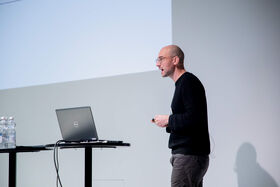 Man speaking in front of a laptop on a podium