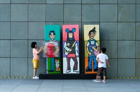 Two children playing with a colorful character combination installation (blocks that can be flipped)