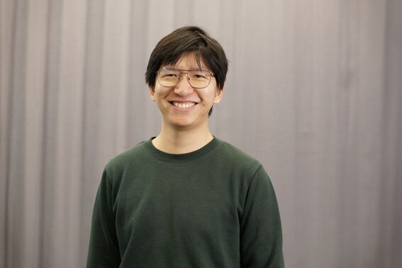 Smiling person wearing glasses against a grey background