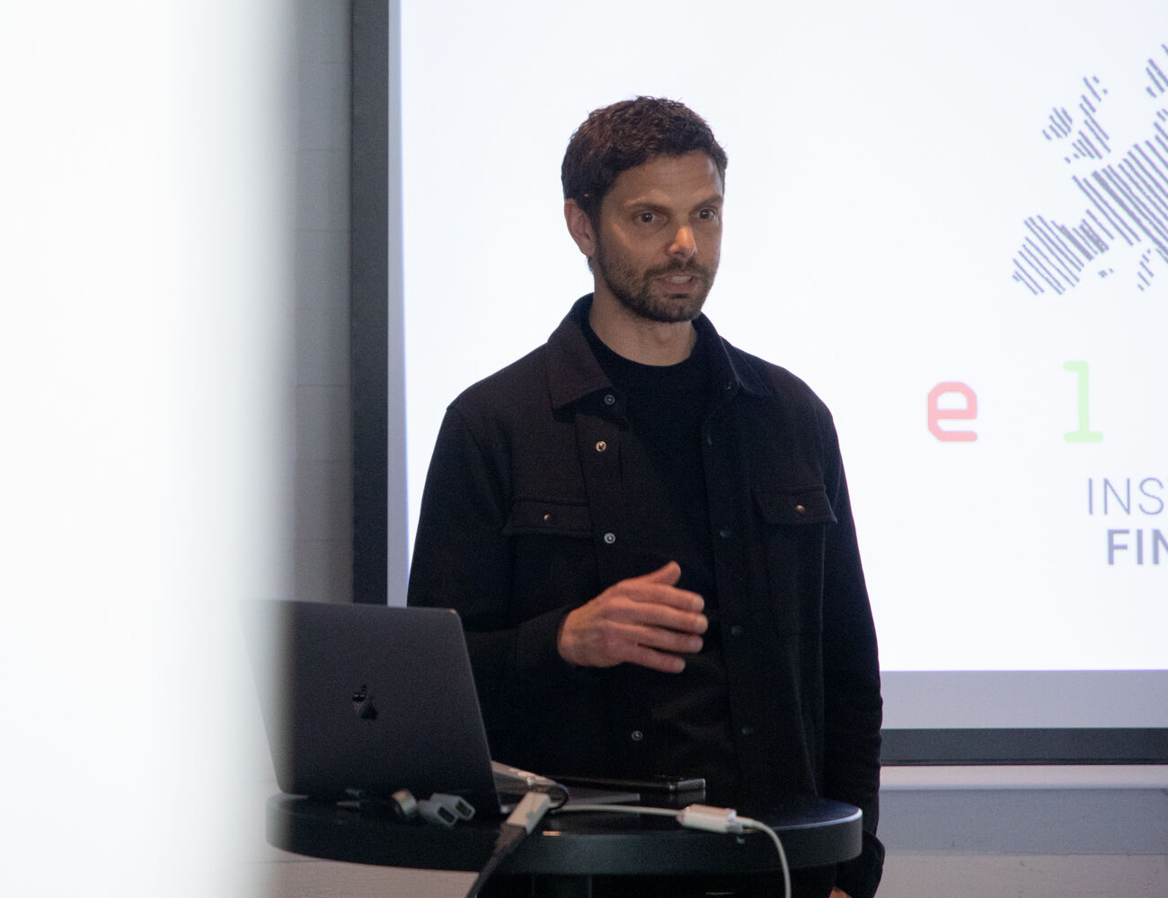 Man speaking in front of a screen