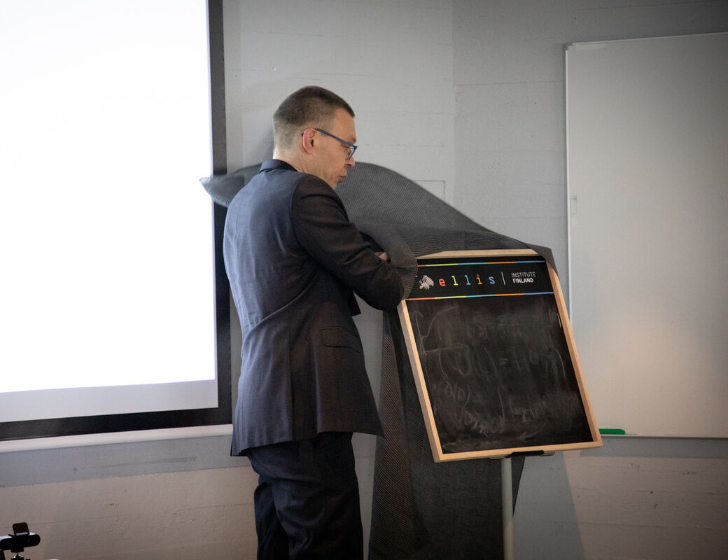 Man lifts cover off of a square blackboard on a stand